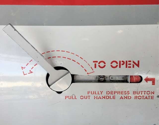 Ein Drehhebel mit der Beschriftung "To Open: Fully depress button, pull out handle and rotate"