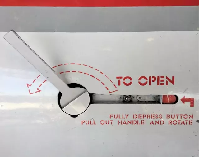 Ein Drehhebel mit der Beschriftung "To Open: Fully depress button, pull out handle and rotate"