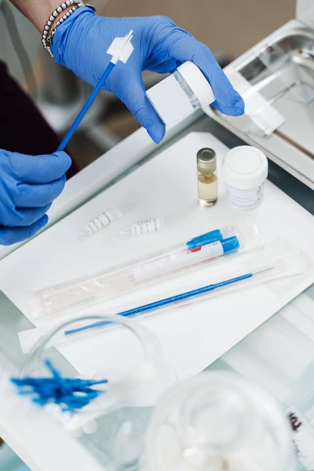 Ein Gynäkologe hält ein Fläschchen für einen zytologischen Pap-Abstrich in den Händen. Er trägt Einmalhandschuhe