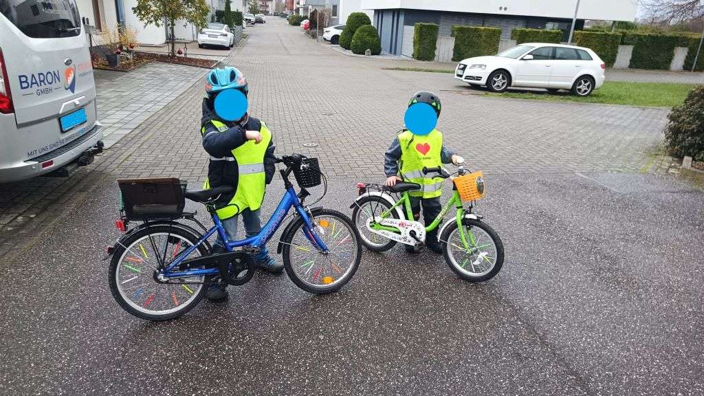 Zwei Kinder mit Warnwesten und Helm auf ihren verkehrssicheren Fahrrädern