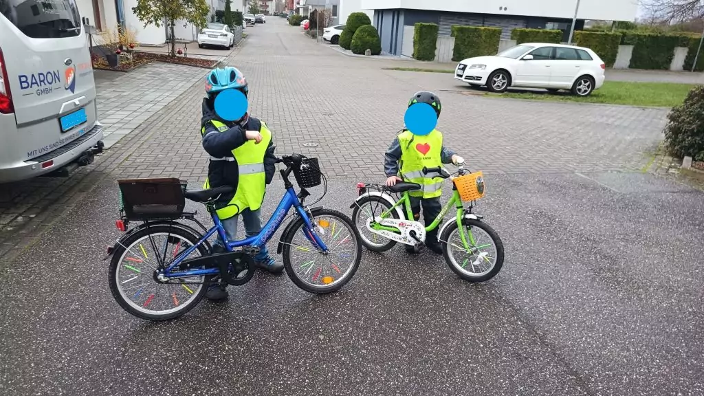 Zwei Kinder mit Warnwesten und Helm auf ihren verkehrssicheren Fahrrädern