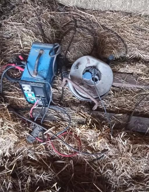 Generator und Kabeltrommel liegen in einem Stall auf Stroh auf dem Boden