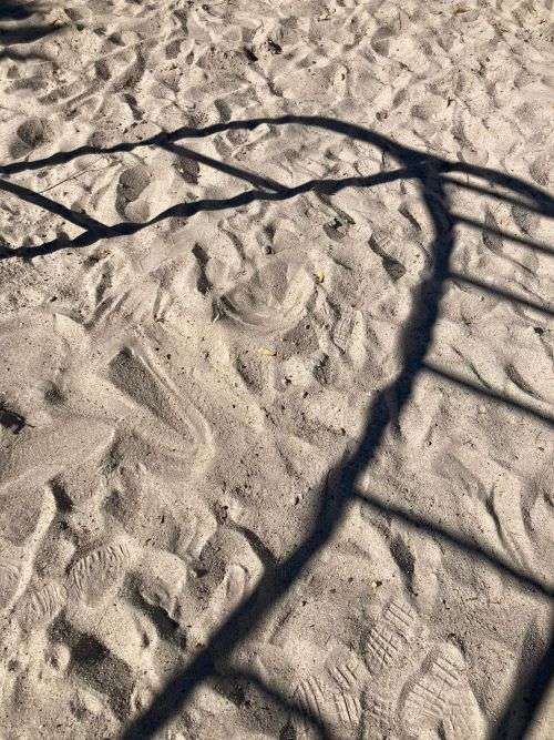 Schatten eines Klettergerüstes auf Sand
